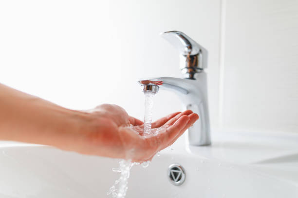 hand under faucet with water stream hand under faucet with water stream, close-up view plumbing fixture stock pictures, royalty-free photos & images