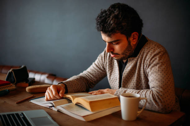 istock Urban Brunette Man is Reading a Book in the Cafe 1132349071