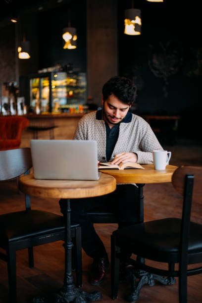 istock Urban Brunette Man is Reading a Book in the Cafe 1132349338