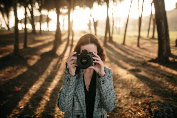 istock Young woman in a forest taking a picture with a DSLR camera 1132350301