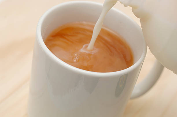 Mug of tea, coffee with milk pouring in