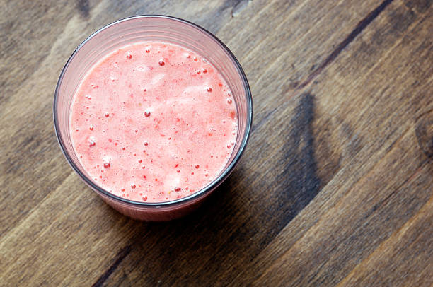 Glass of strawberry fruit smoothie puree on oak table