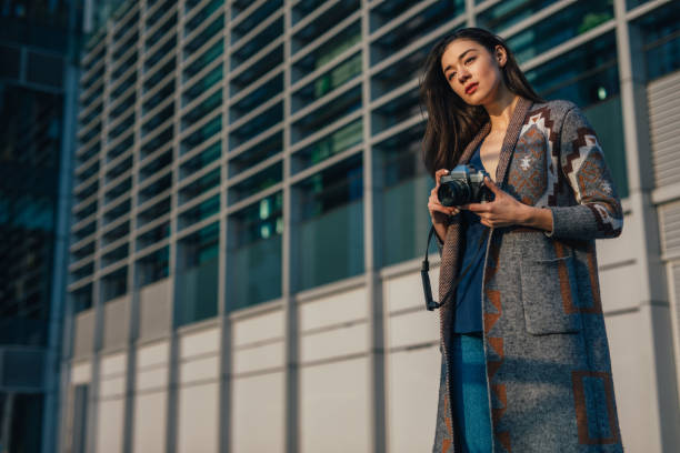 istock Charming woman is holding digital camera 1132360458