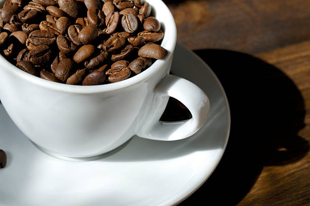 aromatic roasted coffee beans in cup with saucer, lit by natural window light.