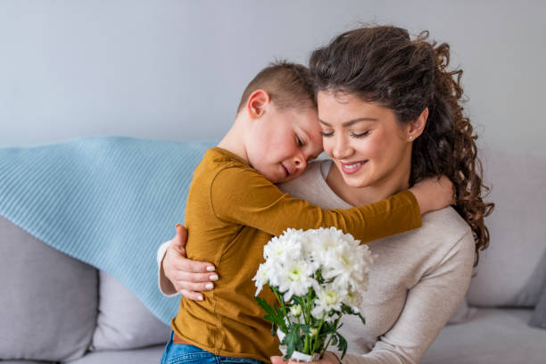 istock Son hugging happy mother with flowers. 1132362725