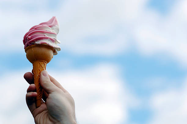 istock Hand holding strawberry ice cream cone against sky 113236462