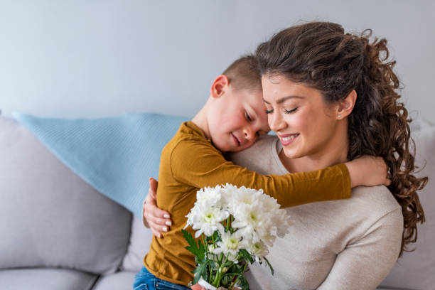 istock Son hugging happy mother with flowers. 1132365438