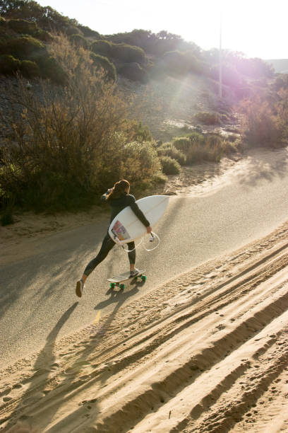 istock Woman surfer with a skateboard on empty road 1132365811