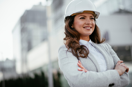 Businesswoman, Architect, Blueprint, Engineer. Female engineer at construction site. Shallow DOF. Developed from RAW; retouched with special care and attention; Small amount of grain added for best final impression. 16 bit Adobe RGB color profile.