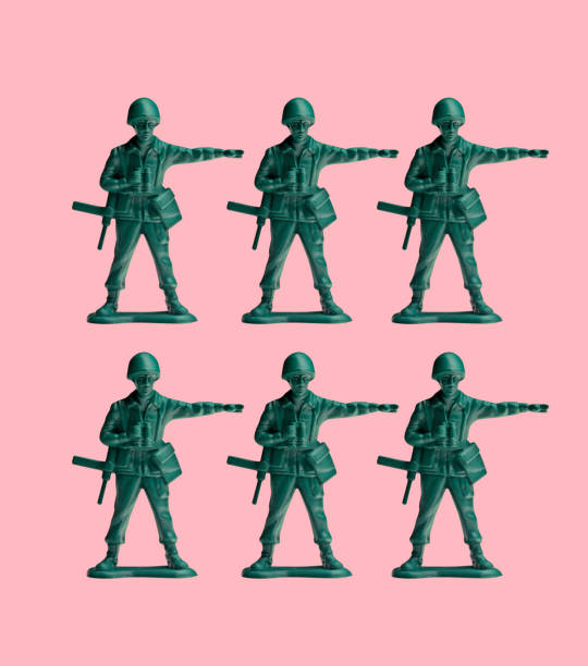 Two Rows Of Green Toy Army Men On A Pink Background Two rows of pointing green army men sit on a pink background. toy soldier stock pictures, royalty-free photos & images