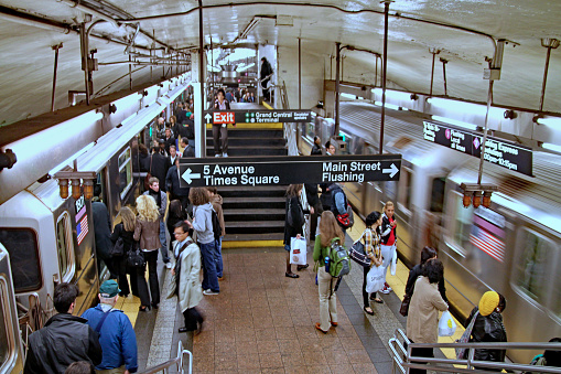 New York Subway, Brooklyn, New York, NY, USA - July 6th 2022: Small group of people waiting for the approaching subway train at the platform at 25th Street subway station
