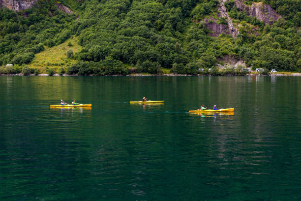 Three kayaks in Geiranger fjord. The Geiranger Fjord- a fjord in the Sunnmore region of More og Romsdal county, Norway. It is one of Norway's most visited tourist sites and  it was listed as a UNESCO World Heritage Site in 2005. Along the fjord's sides there lie a number of now-abandoned farms and  is also host to several impressive waterfalls.