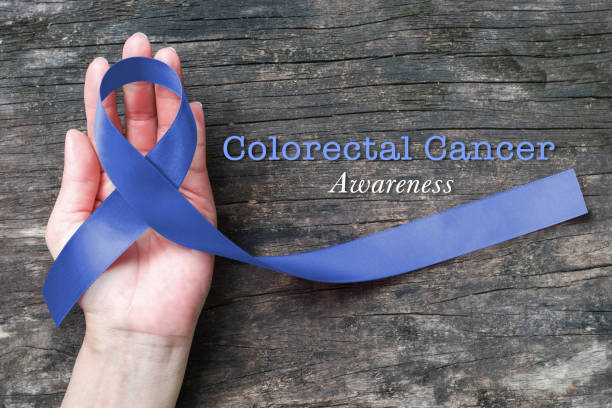 Colorectal or Colon cancer awareness dark blue ribbon on helping hand on old aged woo Colorectal or Colon cancer awareness dark blue ribbon on helping hand on old aged woo colorectal cancer photos stock pictures, royalty-free photos & images