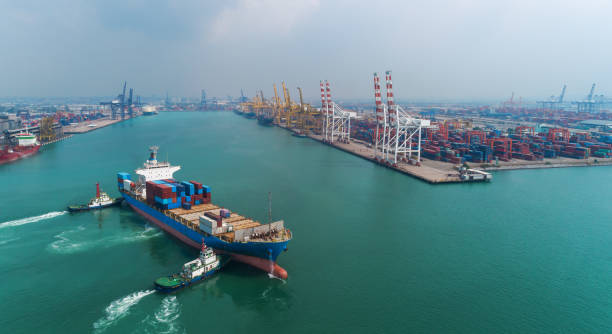 schleppboot ziehen containerschiff zu kranbrücke im seehafen oder containerlager für logistische, importierte export, versand oder transport. - container ship tugboat nautical vessel pulling stock-fotos und bilder