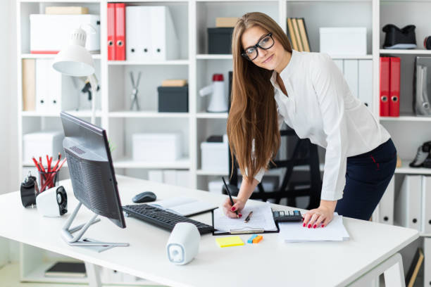 istock A young girl stands bent over near the table and works with a computer, documents and calculator 1132381807