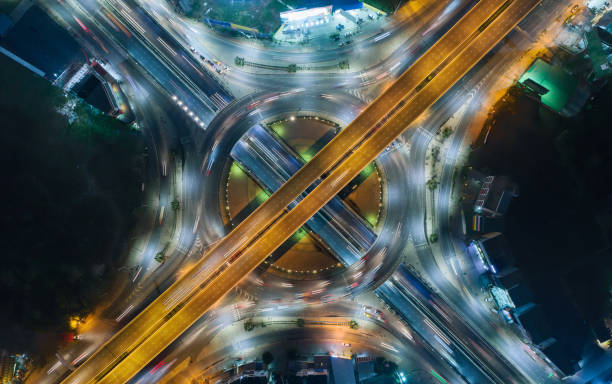 le rond-point d'intersection de route d'autoroute de vue de dessus aérien ou cercle la nuit pour le transport, la distribution ou le trafic arrière-plan. - traffic roundabout photos et images de collection