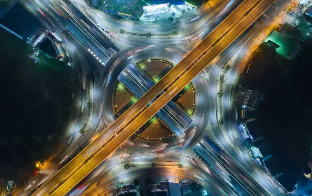 Aerial top view highway road intersection roundabout or circle at night for transportation, distribution or traffic background.