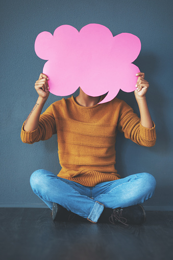 Studio shot of a young woman holding a thought bubble against a grey background