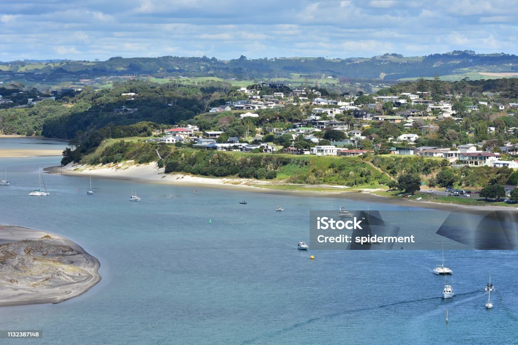 Harbor with houses around View of Mangawhai Harbour with moorings and sand dunes and dense housing of popular holiday destination of Mangawhai Heads. New Zealand Stock Photo