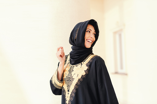 Gorgeous muslim woman with toothy smile and scarf on head posing outdoors.