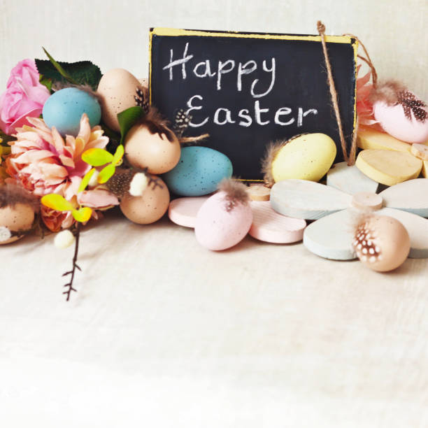 istock Happy Easter message on blackboard with assortment of easter eggs, decorations and flowers, close up 1132392821