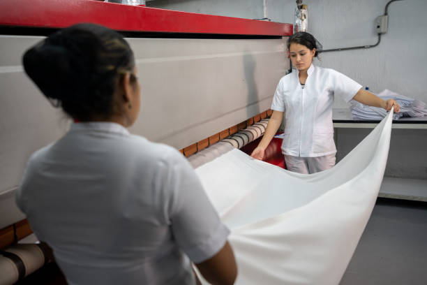 istock Focused woman ironing sheets in an industrial iron 1132394799