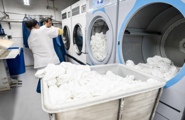 Latin american men working together loading a washing machine at a laundry service Latin american men working together loading a washing machine at a laundry service - Business industry concepts dry cleaner stock pictures, royalty-free photos & images