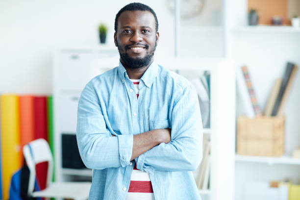 istock Positive handsome young African-American designer with beard standing in modern office and smiling at camera while crossing arms on chest 1132400264