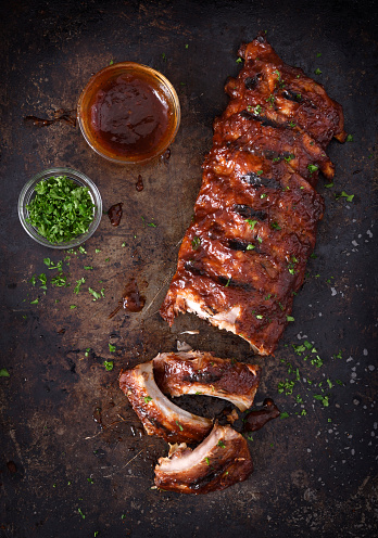 Full rack of grilled barbecue ribs with barbecue sauce on a dark background