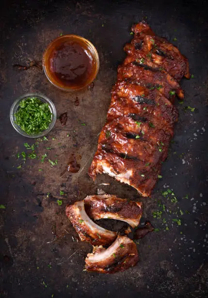 Full rack of grilled barbecue ribs with barbecue sauce on a dark background