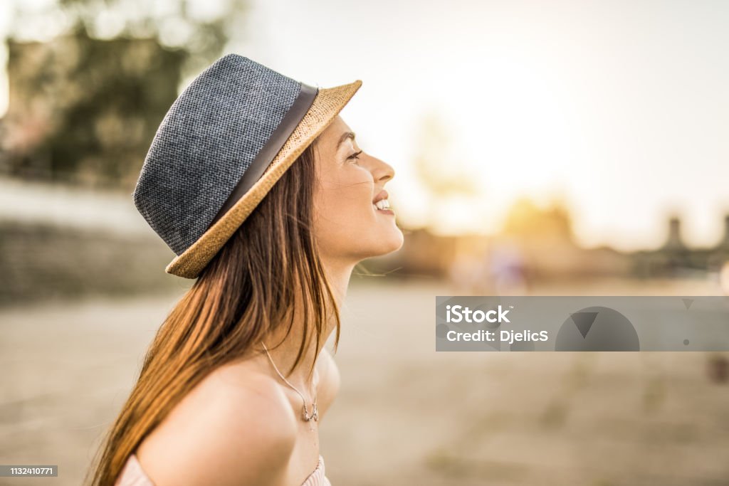 Happy young hipster woman day dreaming on a beautiful sunset in the city. Women Stock Photo