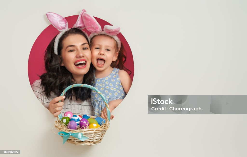Family on Easter Happy holiday! Mother and her daughter with painting eggs. Family preparing for Easter. Cute little child girl is wearing bunny ears. Easter Stock Photo