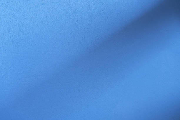 istock bright ultramarine blue cement textured wall with cross black light and black shadow background 1132413790