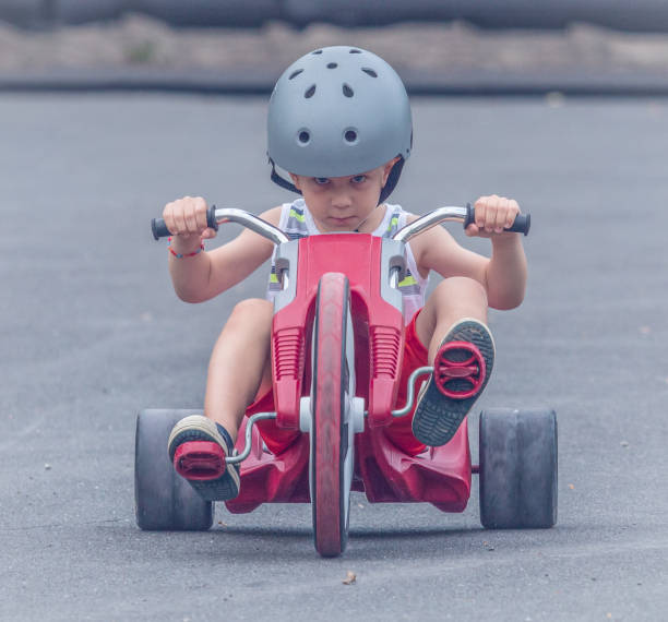 Young Boy Riding a Tricycle A little boy riding a "Big Wheel" tricycle with an look of determination on his face. tricycle stock pictures, royalty-free photos & images