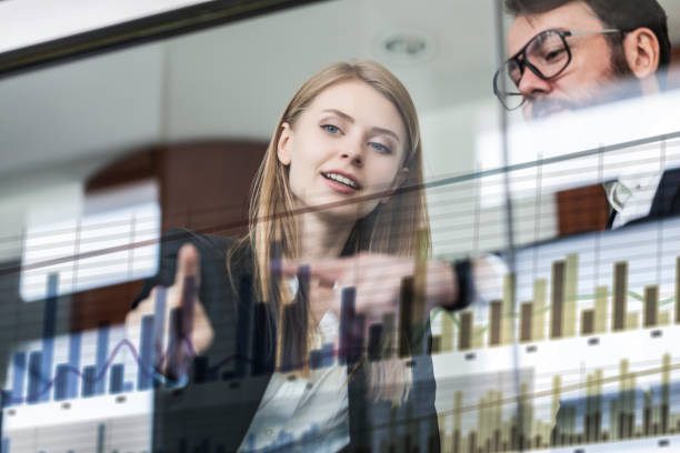 two business persons in front of futuristic display discussing financial graph - polo shirt two people men working imagens e fotografias de stock