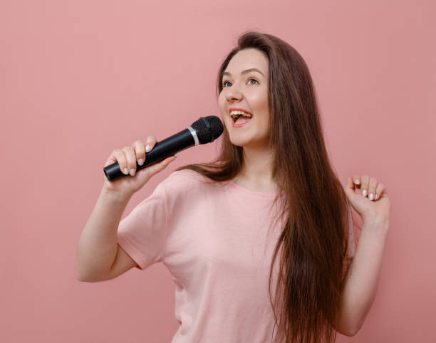 istock young funny woman with microphone in hand on pink background 1132430797