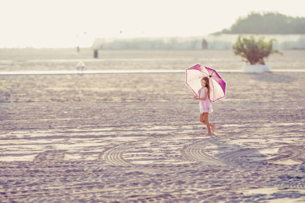 Young Beautiful Girl Walking on Beach With Umbrella.