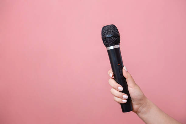 istock microphone in female hand on pink background 1132434659
