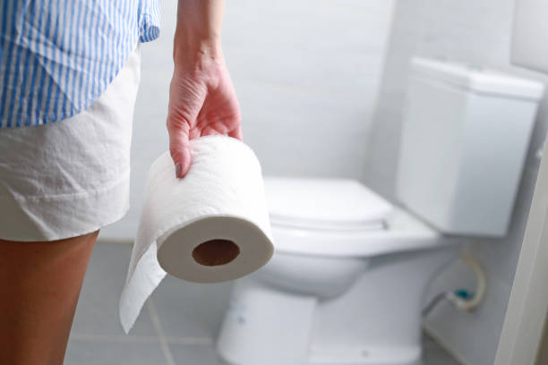 la donna tiene il rotolo di carta igienica davanti alla tazza del water. - toilet paper foto e immagini stock