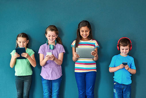 Studio shot of a group of kids using wireless technology against a blue background