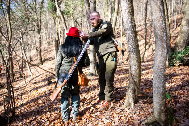 istock Hunter adjusting his female colleague's hat while they hunt in a forest 1132440845