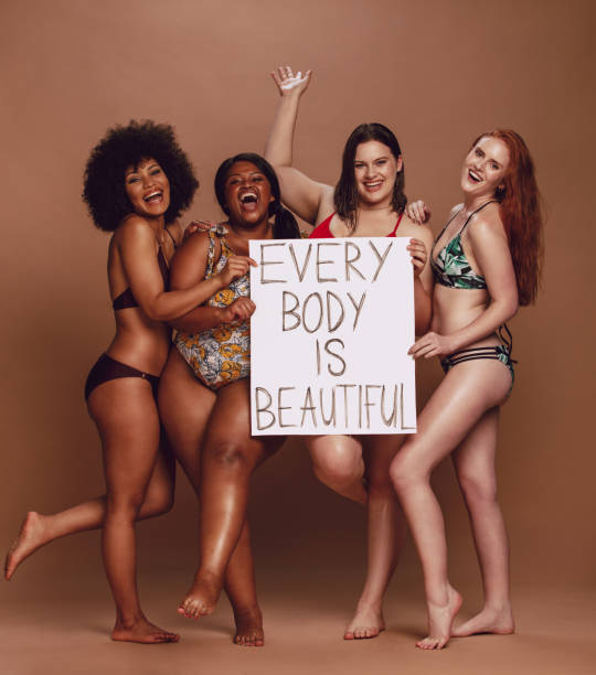istock Cheerful female group with every body is beautiful signboard 1132444552