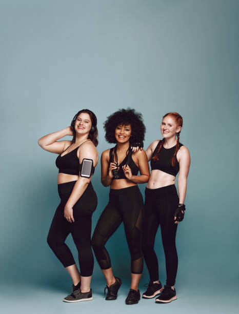 Group of diverse women in sportswear Group of diverse women in sportswear standing together over grey background. Three women of different weight in fitness clothing. beauty in nature vertical africa southern africa stock pictures, royalty-free photos & images
