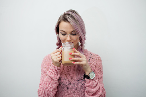 Trendy young woman drinking coffee milkshake. Girl with jar-mug on