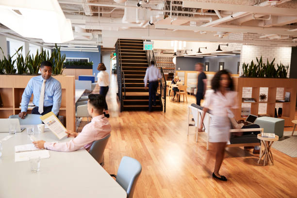 interior view of modern open plan office with blurred businessmen and businesswomen - office time lapse imagens e fotografias de stock