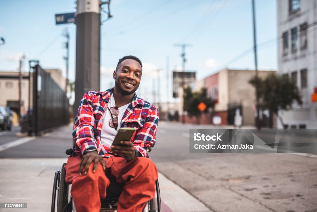 Portrait of an African American disabled men in a wheelchair using smart phone outdoors Wheelchair Stock Photo