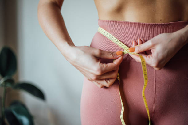 Fit woman measuring her waist stock photo