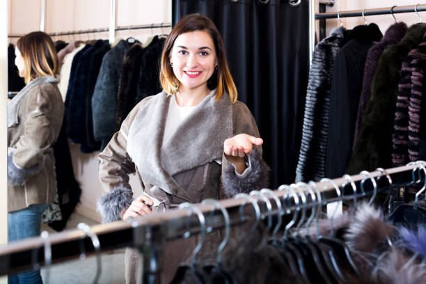 새로운 양 가죽 코트를 검토 하는 여성 고객 - pricy 뉴스 사진 이미지