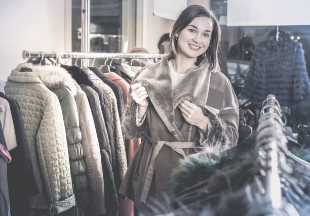 새로운 양 가죽 코트를 검토 하는 여성 고객 - pricy 뉴스 사진 이미지
