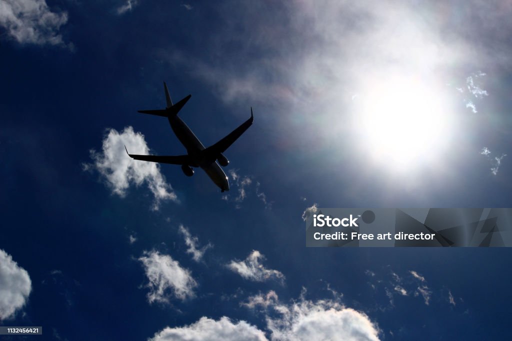 A jet airliner flying under the sun shining in the sky Travel scene Air Vehicle Stock Photo